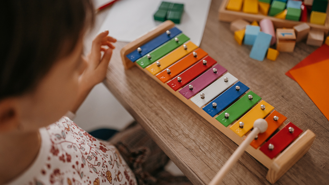 A child uses a mallet to play a xylophone.